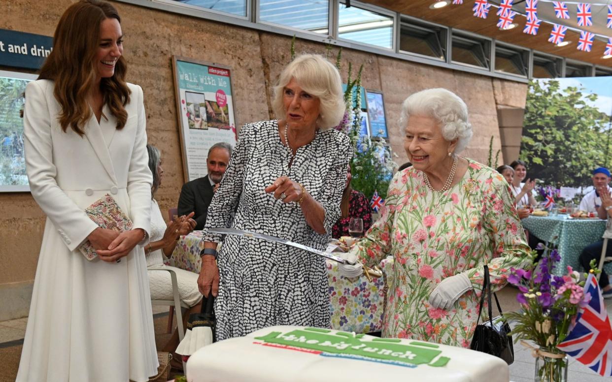 The late Queen holding a large sword for the purposes of cake-cutting