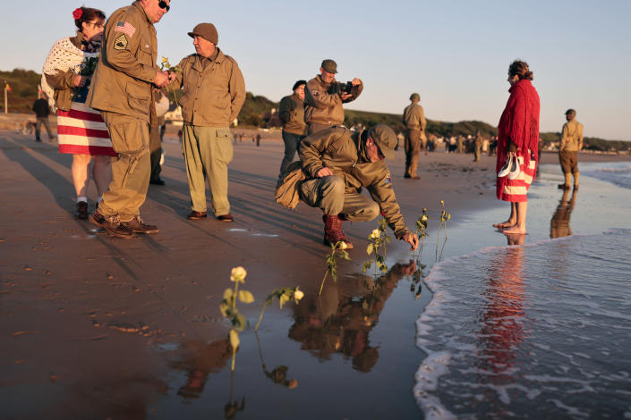 World War II reenactors put roses and flowers at dawn on Omaha Beach, in Saint-Laurent-sur-Mer, Normandy, France Monday, June 6, 2022, the day of 78th anniversary of the assault that helped bring an end to World War II. (AP Photo/Jeremias Gonzalez)