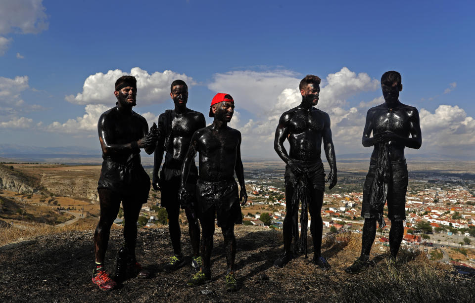 In this photo taken on Friday, Sept. 6, 2019, boys painted with black grease stand on top of a hill during the traditional festivities of the Cascamorras festival in Baza, Spain. During the Cascamorras Festival, and according to an ancient tradition, participants throw black paint over each other for several hours every September 6 in the small town of Baza, in the southern province of Granada. The "Cascamorras" represents a thief who attempted to steal a religious image from a local church. People try to stop him, chasing him and throwing black paint as they run through the streets. (AP Photo/Manu Fernandez)