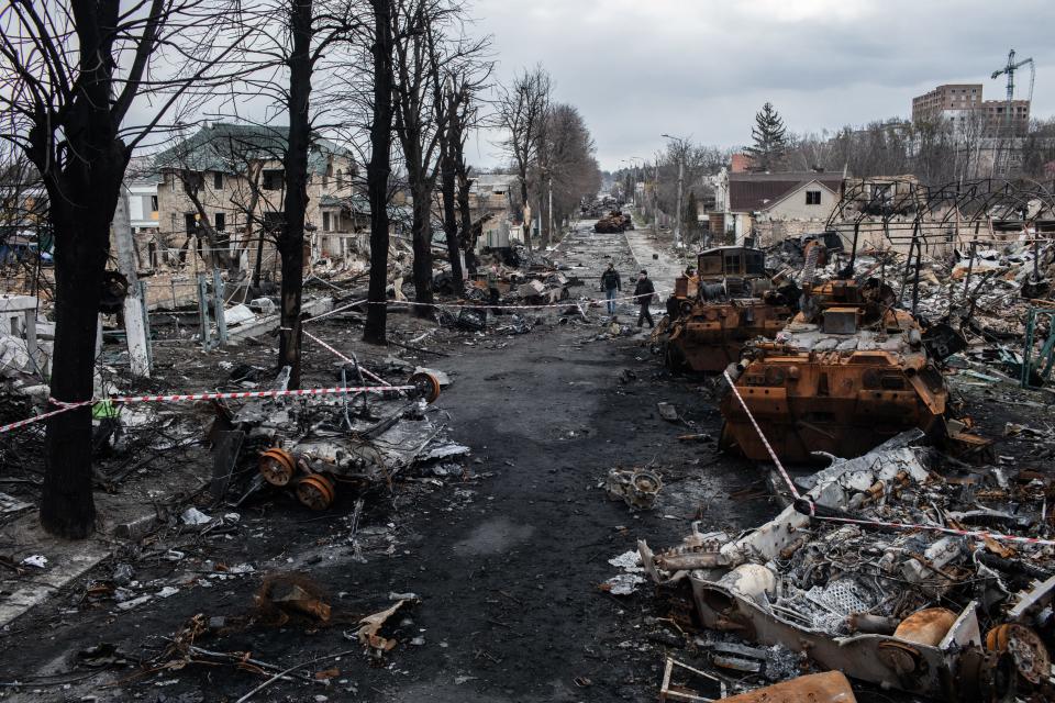 A city street is seen with burnt tanks littered about.