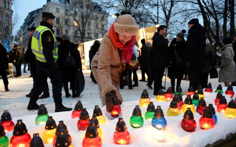 A woman lights a candle during a memorial ceremony for International Holocaust Remembrance Day in Stockholm - Credit: SCANPIX SWEDEN