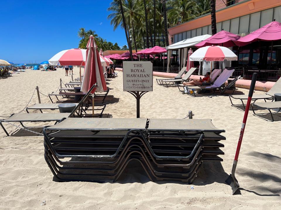 Beach chairs stacked up in front of a sign saying they are for guests of the Royal Hawaiian.