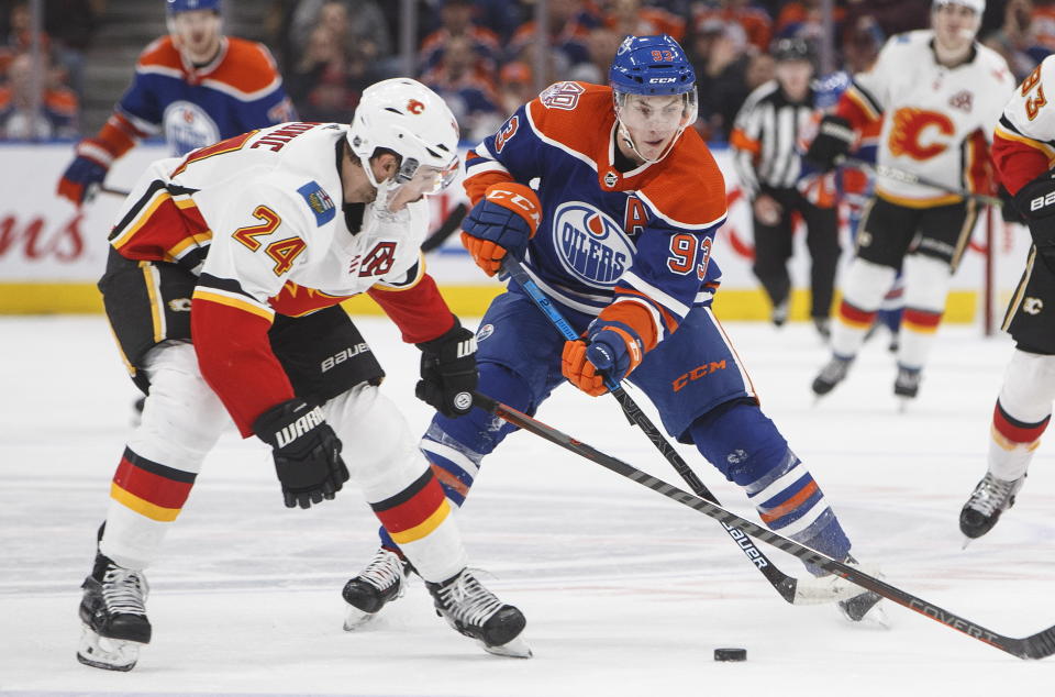 Calgary Flames' Travis Hamonic (24) tries to stop Edmonton Oilers' Ryan Nugent-Hopkins (93) during second period NHL hockey action in Edmonton, Alberta on Sunday, Dec. 9, 2018. (Jason Franson/The Canadian Press via AP)