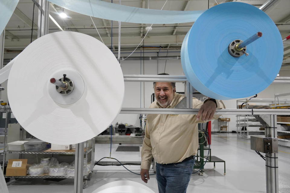 Angstrom Manufacturing president Chris Carron poses for a photo with machinery the company uses to make surgical masks Wednesday, March 23, 2022, in Ste. Genevieve, Mo. Angstrom normally makes dental equipment but expanded with the help of a grant during the pandemic to produce personal protective equipment, churning out millions of surgical-style masks. (AP Photo/Jeff Roberson)