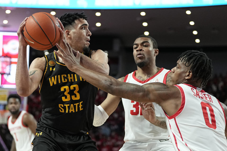Wichita State forward James Rojas (33) is double-teamed by Houston forward Reggie Chaney (32) and guard Marcus Sasser (0) during the first half of an NCAA college basketball game Thursday, March 2, 2023, in Houston. (AP Photo/Kevin M. Cox)