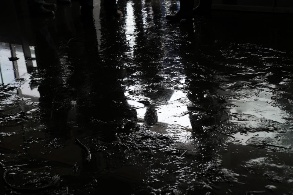 The reflection of Florida Gov. Ron DeSantis is seen in mud and water coating the floor, as he speaks with the owners of Shrimp Boat, Horseshoe Beach's only restaurant, which filled with storm surge and suffered damage during the passage of Hurricane Idalia one day earlier, in Horseshoe Beach, Fla., Thursday, Aug. 31, 2023. (AP Photo/Rebecca Blackwell)