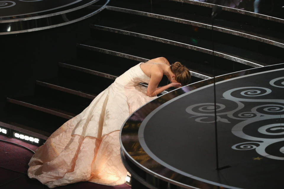 Actress Jennifer Lawrence in a ball gown after stumbling on the stairs, covers her face after winning the Best Actress award for 'Silver Linings Playbook' during the Oscars held at the Dolby Theatre on February 24, 2013 in Hollywood, California.  