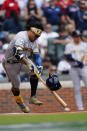 Milwaukee Brewers second baseman Kolten Wong (16) loses his helmet as he grounds out during the first inning of Game 3 of a baseball National League Division Series against the Atlanta Braves, Monday, Oct. 11, 2021, in Atlanta. (AP Photo/John Bazemore)
