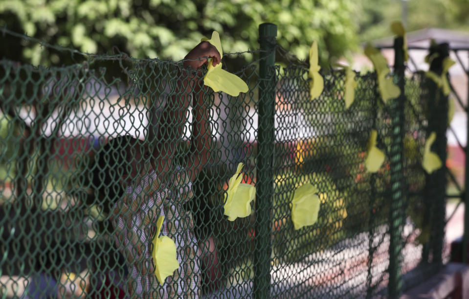 Niños sujetan mariposas amarillas de papel a la cerca de un jardín de infantes que funciona en la antigua escuela primaria del difunto escritor Gabriel García Márquez en Aracataca, Colombia, lunes 21 de abril de 2014. El premio Nobel de literatura era homenajeado en la ciudad de México, donde vivió muchos años hasta su muerte el jueves pasado, y en Aracataca. Las mariposas evocan un célebre pasaje de "Cien años de soledad", la obra maestra de García Márquez. (AP Foto/Ricardo Mazalan)