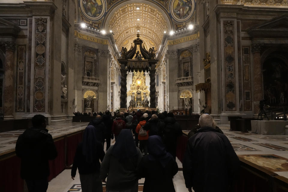 Fieles entran a la basílica de San Pedro, donde está instalada la capilla ardiente del papa emérito Benedicto XVI, en el Vaticano, el 4 de enero de 2023. (AP Foto/Gregorio Borgia)