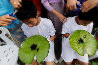 Boys have their hair cut in preparation for an annual Poy Sang Long celebration, a traditional rite of passage for boys to be initiated as Buddhist novices, in Mae Hong Son, Thailand, April 2, 2018. Their shorn hair is wrapped in lotus leaves and saved as a keepsake by their mothers. REUTERS/Jorge Silva