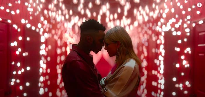 A couple embraces in a room lit by christmas lights