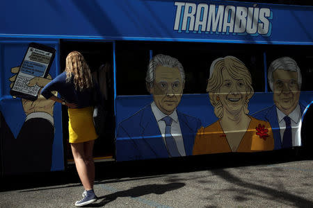 A reporter waits to get on board a bus sponsored by Podemos (We can) party painted with pictures representing Spain's recent political scandals before touring Madrid, Spain April 18, 2017. Picture taken April 18, 2017. REUTERS/Susana Vera