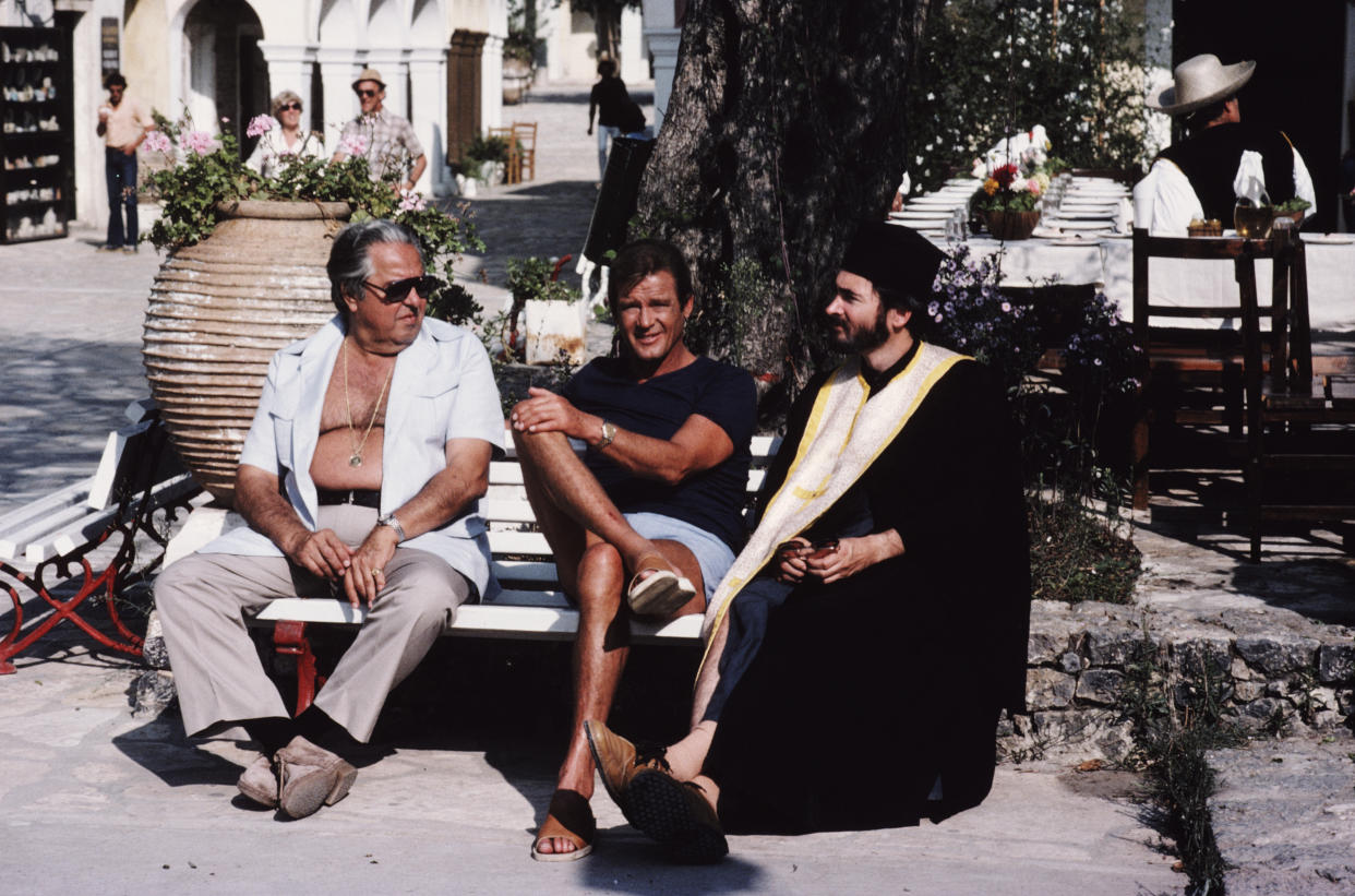 From left to right, producer Albert R. Broccoli (1909 - 1996), English actor Roger Moore and producer and screenwriter Michael G. Wilson on the set of the James Bond film 'For Your Eyes Only', 1981. Wilson is in costume for his customary bit-part, this time as a Greek Orthodox priest. (Photo by Keith Hamshere/Getty Images) 