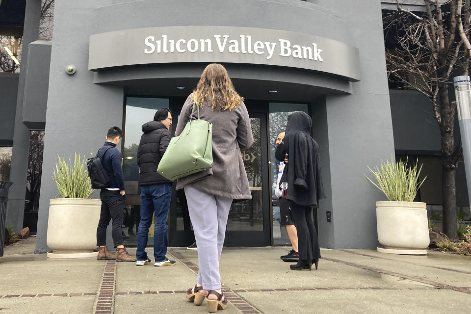 File - People stand outside a Silicon Valley Bank branch in Santa Clara, Calif., Friday, March 10, 2023. The Federal Reserve is scheduled Friday to release a highly-anticipated review of its supervision of Silicon Valley Bank, the go-to bank for venture capital firms and technology start-ups that failed spectacularly in March. (AP Photo/Jeff Chiu, File)