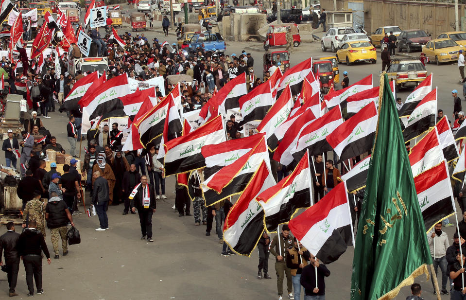 People hold national flags and chanting religious slogans march in Tahrir Square in Baghdad, Iraq, Friday, Dec. 6, 2019. (AP Photo/Hadi Mizban)