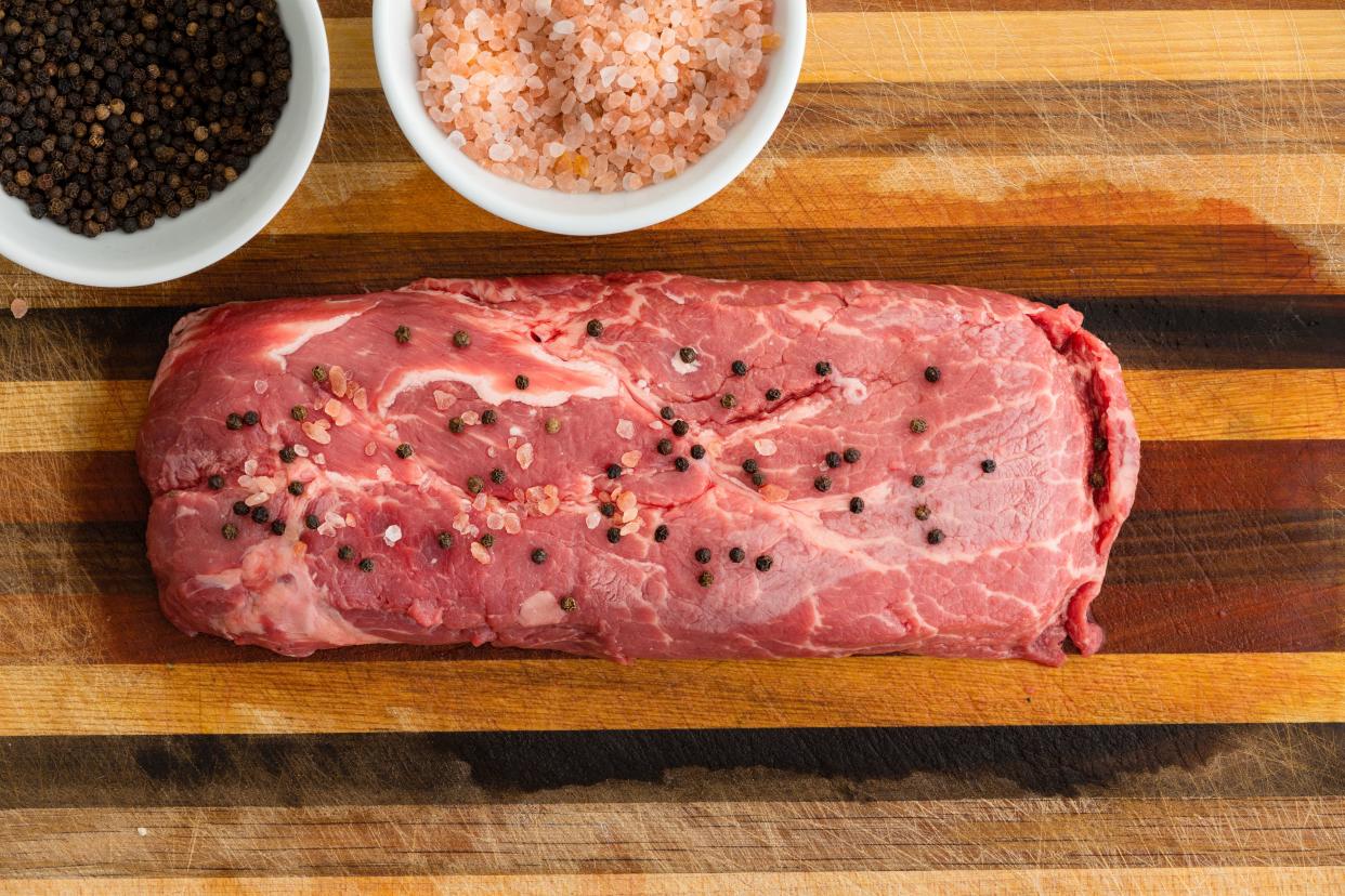 Raw Flat Iron Steak covered with pepper corns