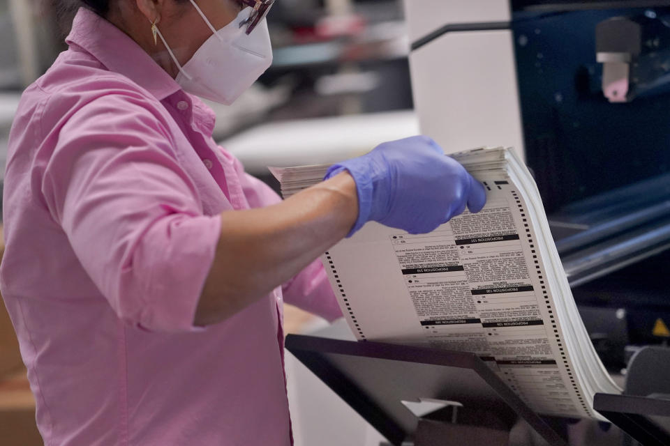 An election worker removes tabulated ballots from the machine inside the Maricopa County Recorders Office, Thursday, Nov. 10, 2022, in Phoenix. (AP Photo/Matt York)