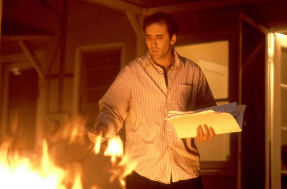Nicolas Cage tosses paper into a fire