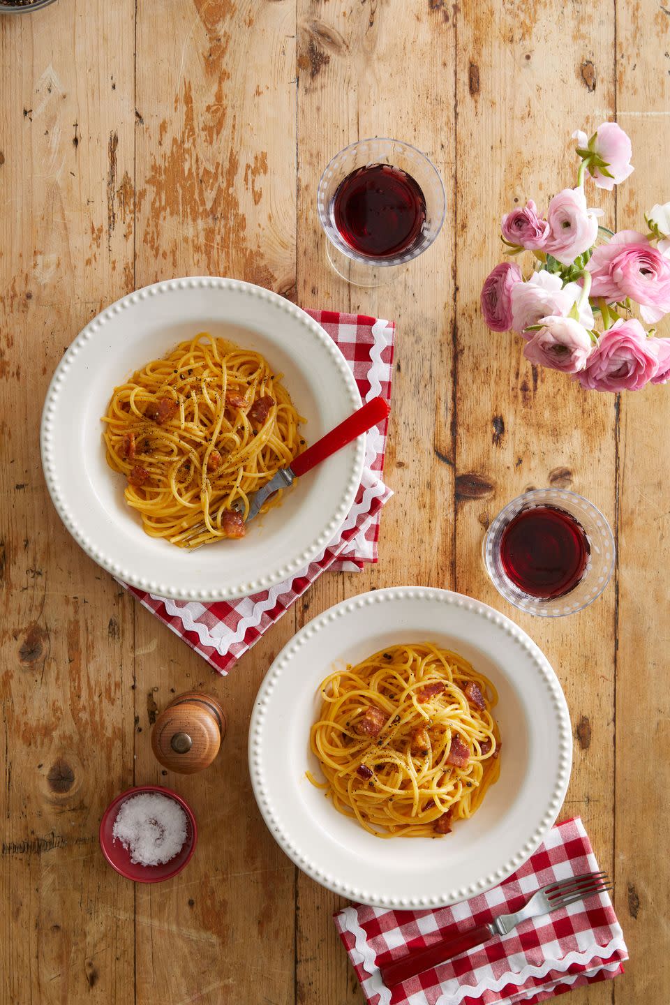 pasta carbonara on a table with wine and roses