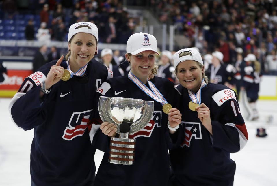 FILE - U.S. forward Meghan Duggan, left, defender Monique Lamoureux, center, and forward Brianna Decker pose with the winner's trophy after the team defeated Canada 3-2 in overtime in the women's world hockey championships in Plymouth, Mich., April 7, 2017. Olympic gold medalist and six-time world champion Brianna Decker announced her retirement from the U.S. Women’s National Team, Thursday, March 2, 2023. (AP Photo/Carlos Osorio, File)