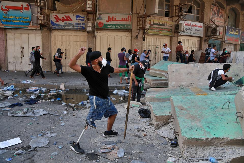 A protester with a prosthetic leg prepares to throw a stone during clashes between Iraqi security forces and anti-government protesters, in downtown Baghdad, Iraq, Monday, Nov. 11, 2019. (AP Photo/Khalid Mohammed)
