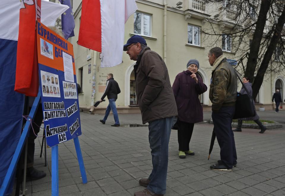 In this photo taken on Monday, Nov. 11, 2019, People look at an election's poster in Minsk, Belarus, ahead of the parliamentary election to be held on Sunday. (AP Photo/Sergei Grits)