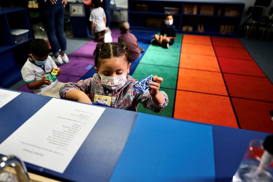 A child wearing a mask plays with toys at kindergarten