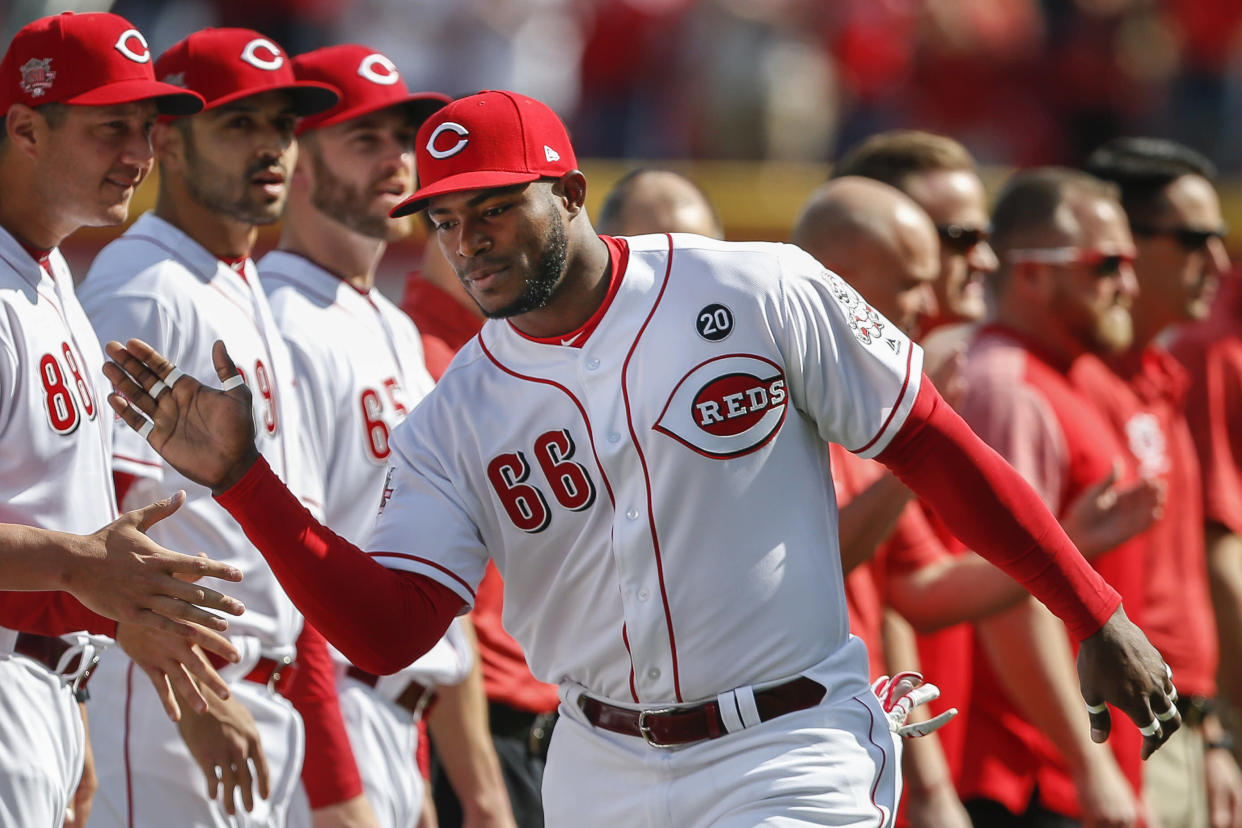 Cincinnati Reds right fielder Yasiel Puig greets his teammates before an opening day baseball game against the Pittsburgh Pirates, Thursday, March 28, 2019, in Cincinnati. (AP Photo/Gary Landers)