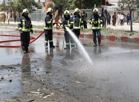 Afghan firefighters clean the site of a suicide car bomb attack in Kabul, Afghanistan