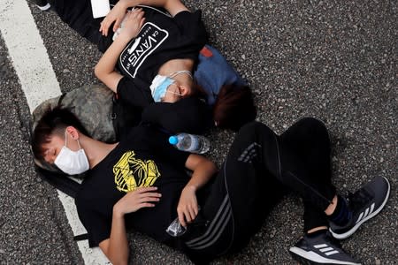 Protesters rest along a road near a police headquarters during a demonstration demanding Hong Kong's leaders to step down and withdraw the extradition bill, in Hong Kong