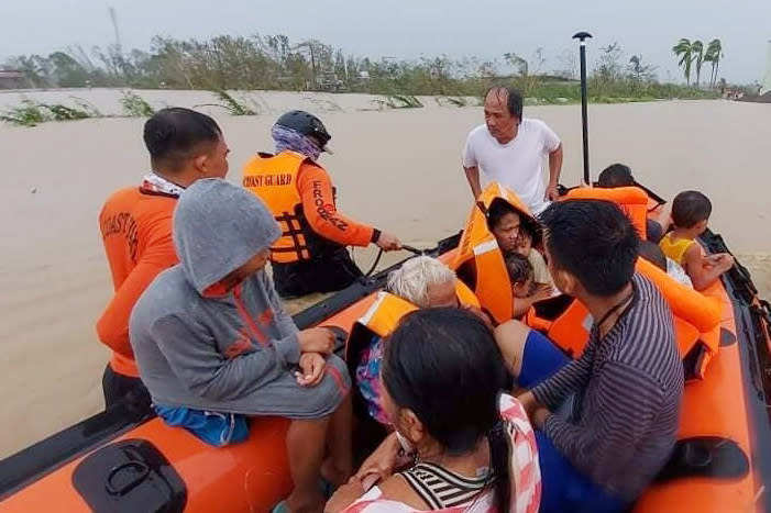 CORRECTS THE AREA TO NEGROS OCCIDENTAL, INSTEAD OF LOBOC, BOHOL - In this photo provided by the Philippine Coast Guard, rescuers assist residents who were trapped in their homes after floodwaters caused by Typhoon Rai inundated their village in Negros Occidental, central Philippines, on Friday, Dec. 17, 2021. The strong typhoon engulfed villages in floods that trapped residents on roofs, toppled trees and knocked out power in southern and central island provinces, where more than 300,000 villagers had fled to safety before the onslaught, officials said. (Philippine Coast Guard via AP)