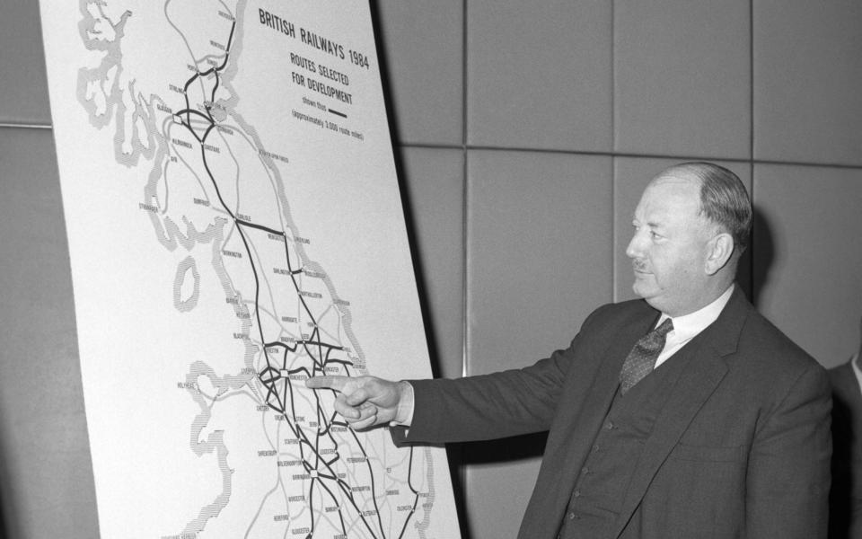 Richard Beeching looking at a large map, showing how British Rail trunk routes might look in 1984 