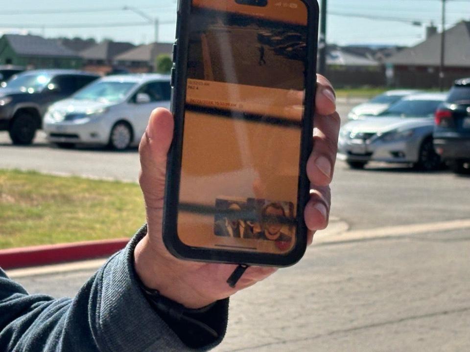 Angel Protection executive Lewis Matthews holds up his phone to the crowd as the alert sounds so they can see the image captured by security cameras Tuesday. The photo captured by the camera on the Wylie ISD Performing Arts Center is of Angel Protection executive Carlos Ortiz walking through the Wylie High School parking lot carrying a large weapon.