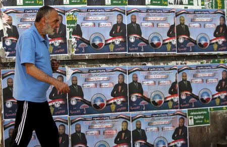 A man walks past election posters for parliamentary candidates of the Nour party Hossam Abdo and Mohammed Osama in the Imbaba district of Giza, Egypt, October 13, 2015. REUTERS/Mohamed Abd El Ghany