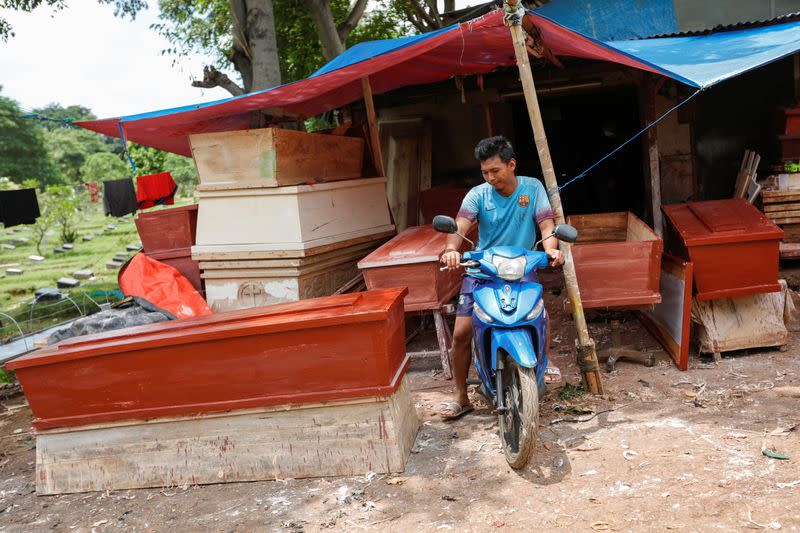 Ari Rusmawan, a 32-year-old coffins maker, rides a motorbike while leaving their workshop for lunch as he takes a break on preparing coffins ordered to be donated for the coronavirus disease (COVID-19) victims inside a funeral complex in Jakarta