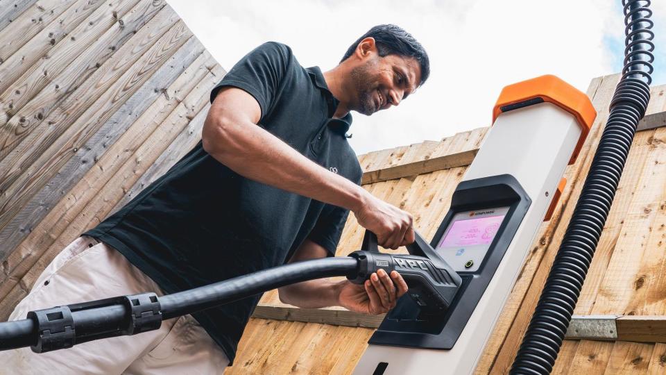 Sai Shivareddy smiling, in a black polo shirt, plugging in the charging cable for the new car