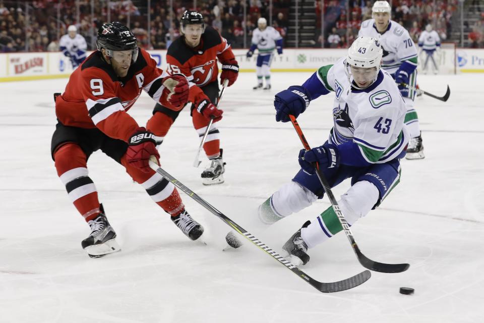 New Jersey Devils' Taylor Hall (9) fights for control of the puck with Vancouver Canucks' Quinn Hughes (43) during the first period of an NHL hockey game Saturday, Oct. 19, 2019, in Newark, N.J. (AP Photo/Frank Franklin II)