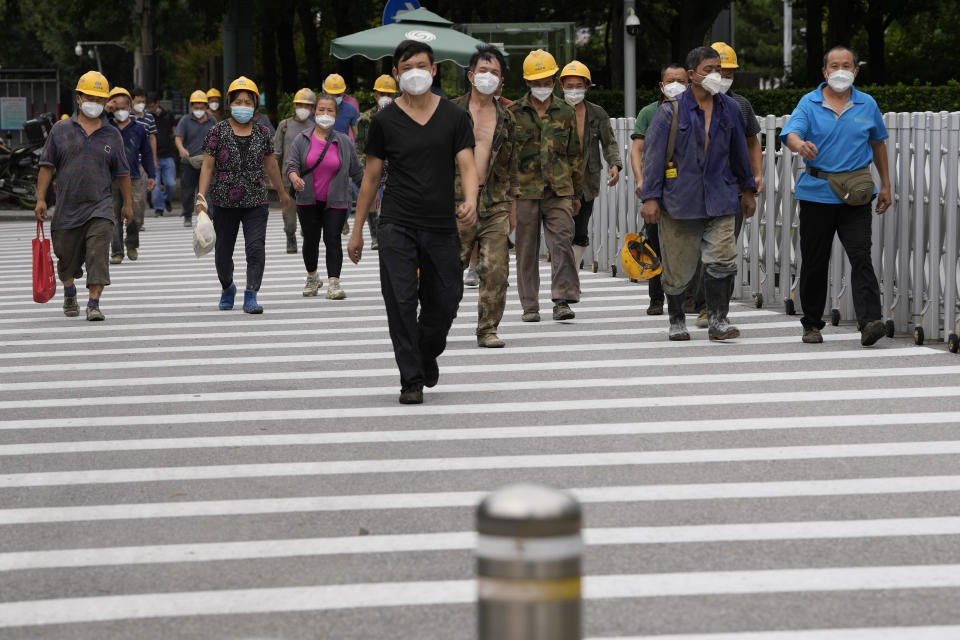 Construction workers wearing masks walk to their work site in Beijing, Monday, Aug. 15, 2022. China’s central bank trimmed a key interest rate Monday to shore up sagging economic growth at a politically sensitive time when President Xi Jinping is believed to be trying to extend his hold on power. (AP Photo/Ng Han Guan)