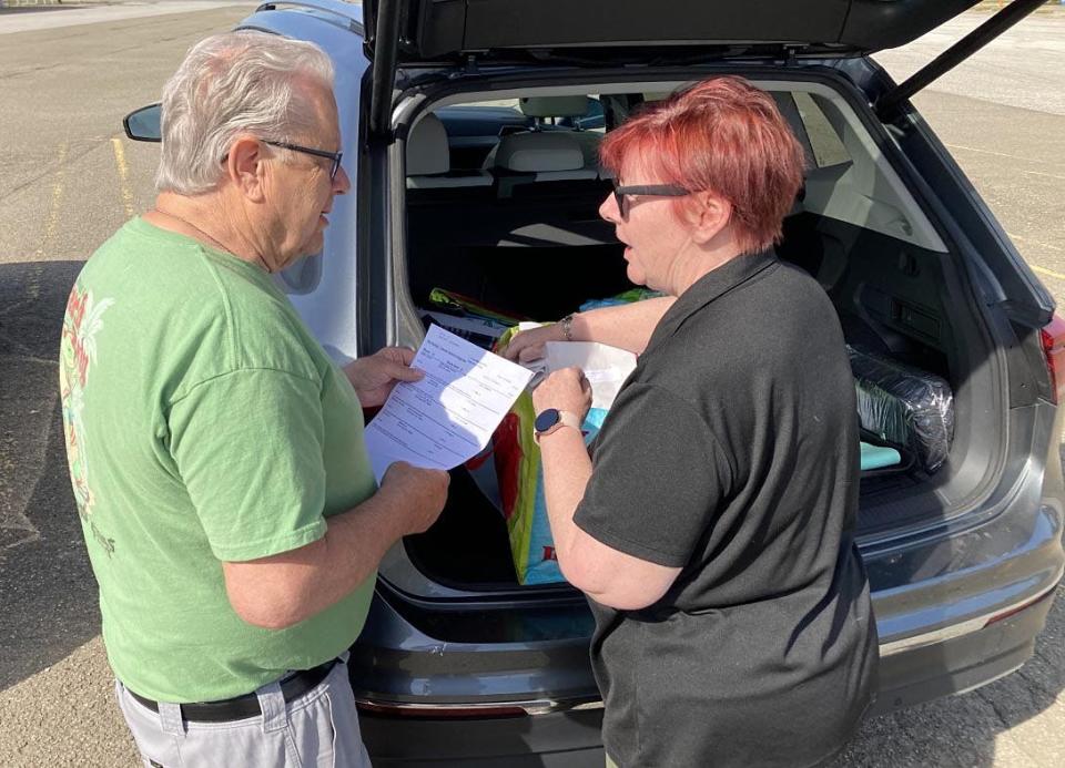 Mary Beth Ford, right, assistant director for Meals on Wheels, drops off meals and goes over a client list with volunteer driver Gary Post on May 11 in the former KMart plaza in Harborcreek Township.