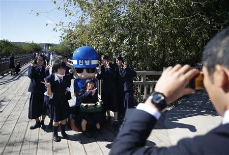 Japanese students pose for a photo with a statue of a South Korean military policeman at the Imjingak pavilion near the demilitarized zone which separates the two Koreas, in Paju, north of Seoul October 16, 2013. REUTERS/Kim Hong-Ji