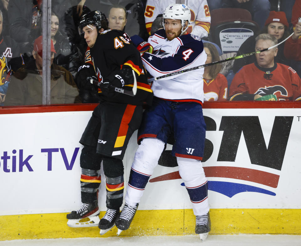 Columbus Blue Jackets defenseman Vladislav Gavrikov, right, is checked by Calgary Flames forward Jakob Pelletier during first-period NHL hockey game action in Calgary, Alberta, Monday, Jan. 23, 2023. (Jeff McIntosh/The Canadian Press via AP)