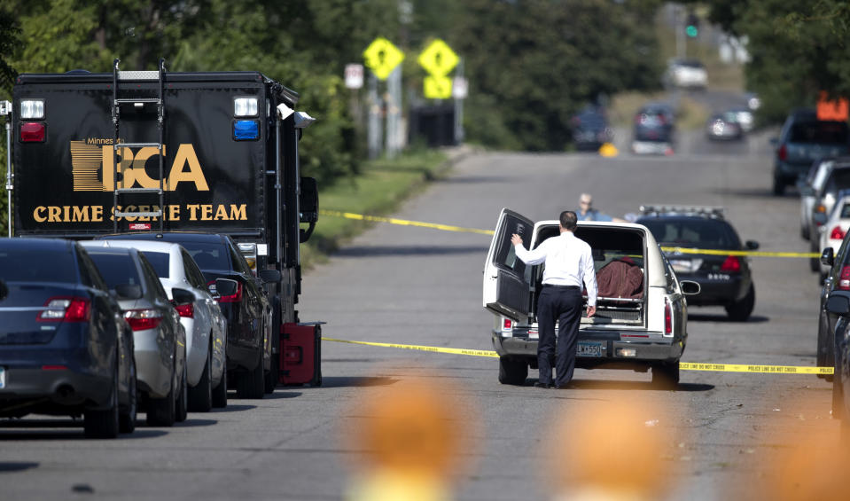 The Ramsey County corner loads the body of a person that was shot and killed by St. Paul Police in the 900 block of St. Anthony Avenue, Sunday, Aug. 5, 2018 in St. Paul, Minn. Police say officers shot an armed man while responding to a 911 call early Sunday about shots fired at a home. (Jerry Holt/Star Tribune via AP)