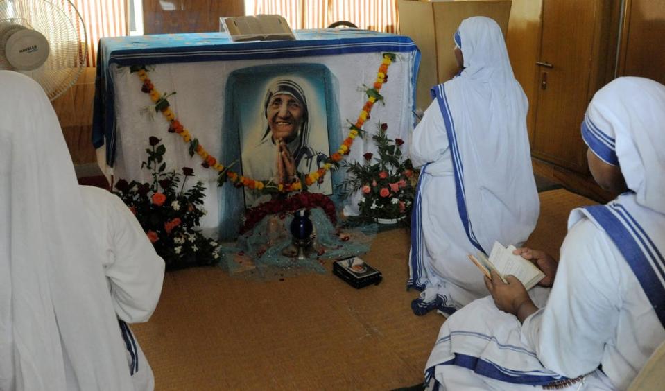 Christian nuns pray in front of a photograph of Mother Teresa as they observe the fifteenth anniversary of her death  (AFP via Getty)