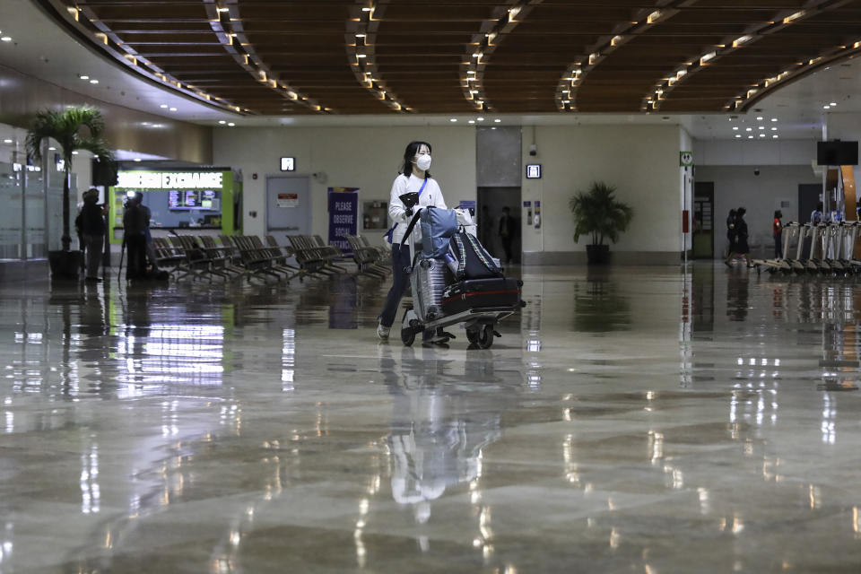 A foreign passenger wearing a protective mask as a precaution against the spread of the coronavirus pushes her cart as she arrives at Manila's International Airport, Philippines Thursday, Feb. 10, 2022. The Philippines lifted a nearly 2-year ban on foreign travelers Thursday in a lifesaving boost for its tourism and related industries as an omicron-fueled surge eases. (AP Photo/Basilio Sepe)