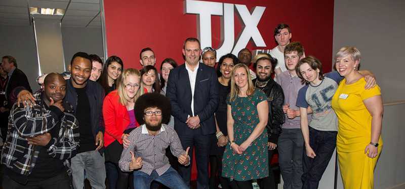 A group of people in front of a TJX red wall.
