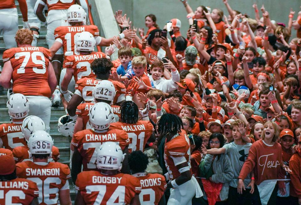 Texas players high-five with fans before a game at Royal-Memorial Stadium. College athletes going back to 2016 will be part of a landmark $2.8 billion settlement with the NCAA that paves the way for players to be paid.