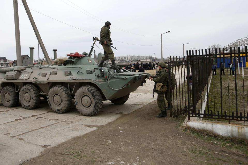 Military personnel stand next to an APC in the Crimean port city of Feodosiya