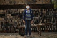 Ronnie, 10, wearing a mask to curb the spread of the new coronavirus, poses for a portrait as he works alongside his father at a small brick factory in Tobati, Paraguay, Monday, Aug. 31, 2020. Members of brickmaking families said school closures, scheduled to last at least until December, have led to many children and adolescents working longer hours, making it difficult to complete their virtual schoolwork. (AP Photo/Jorge Saenz)