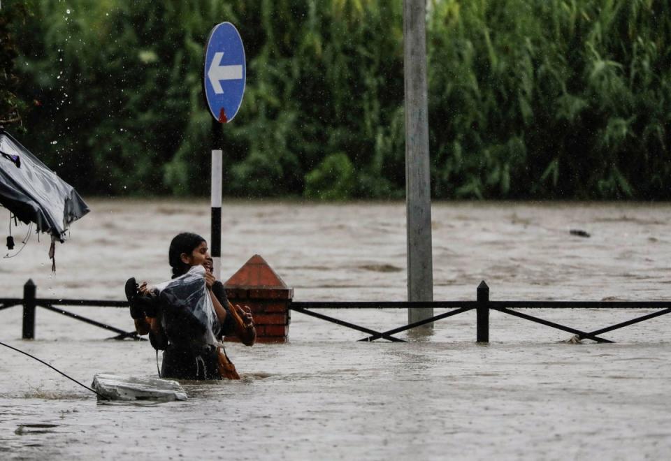 A woman carrying her belongings wades through a flooded road along the bank of the overflowing Bagmati river following heavy rains in Kathmandu, Nepal (REUTERS)